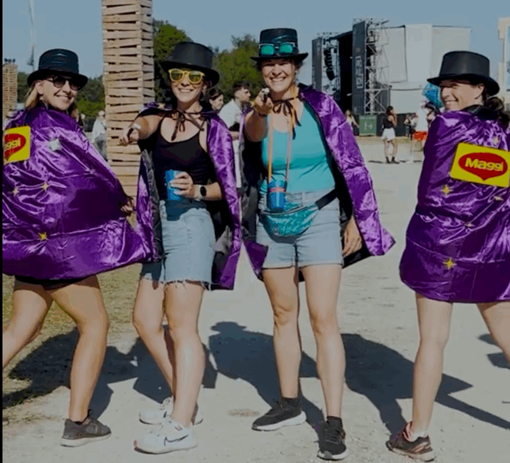 4 festivalières en costume de magicien, avec le logo Maggi dans le dos